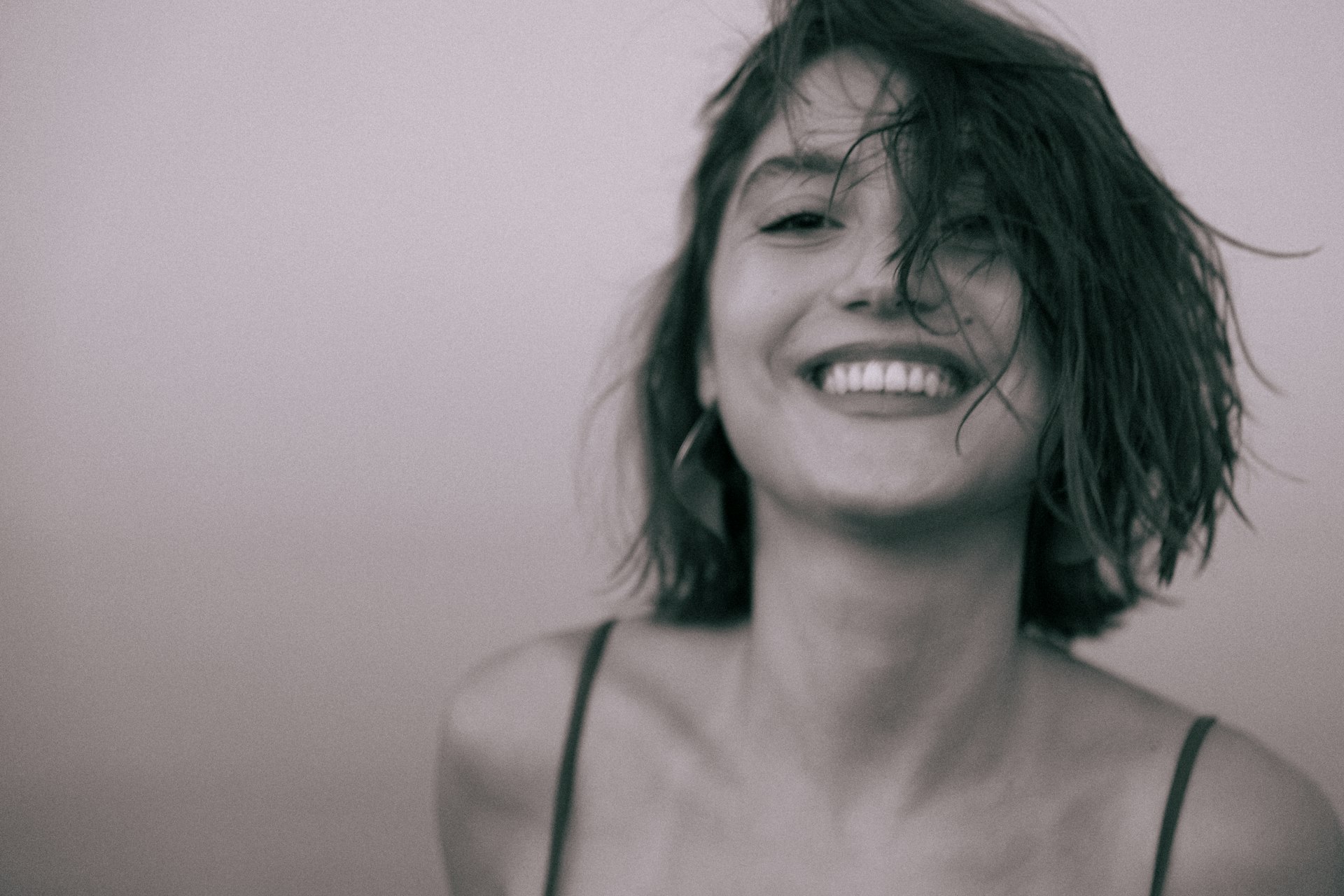 A woman with wet hair smiling and holding a cell phone